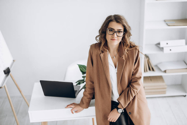 Beautiful and clever girl in glasses and in stylish clothes in her bright office - Foto, Imagem