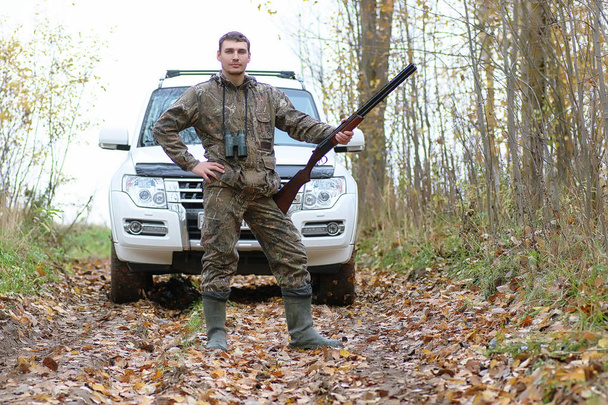 Hombre en camuflaje y con armas en un cinturón forestal en un hun de primavera
 - Foto, imagen