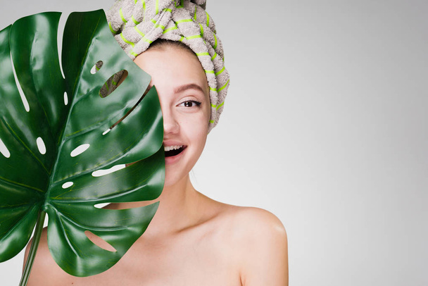 happy woman with a towel on her head holds a large leaf - Foto, afbeelding