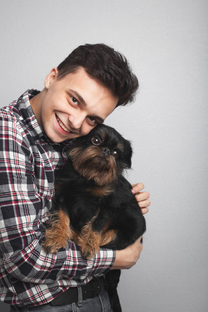 Closeup portrait handsome young hipster man, kissing his good friend black dog isolated light background. Positive human emotions, facial expression, feelings - Photo, Image