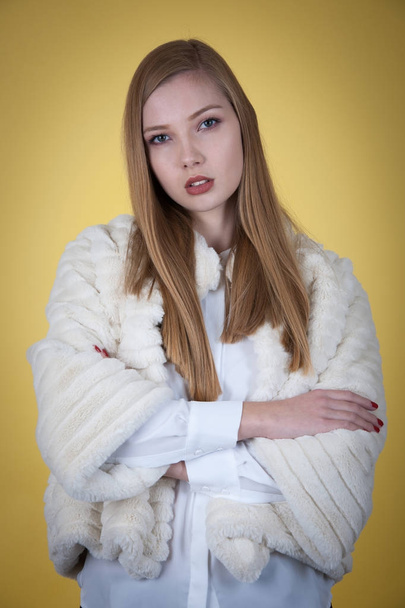 Beauty portrait of woman in fur winter jacket over yellow backgr - Fotografie, Obrázek