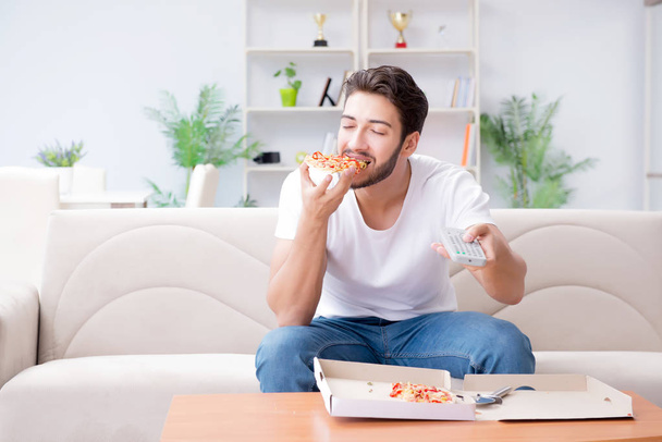 Man eating pizza having a takeaway at home relaxing resting - Zdjęcie, obraz