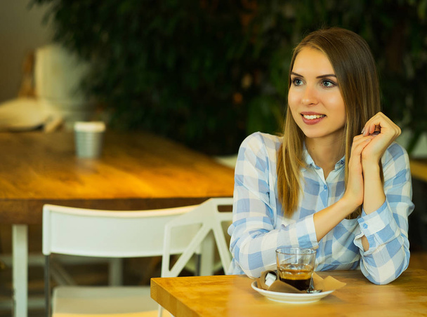 Усміхнена жінка в хорошому настрої з чашкою кави, сидячи в кафе
. - Фото, зображення