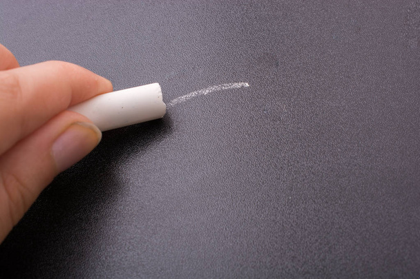 Hand holding  white chalk and black board - Foto, afbeelding