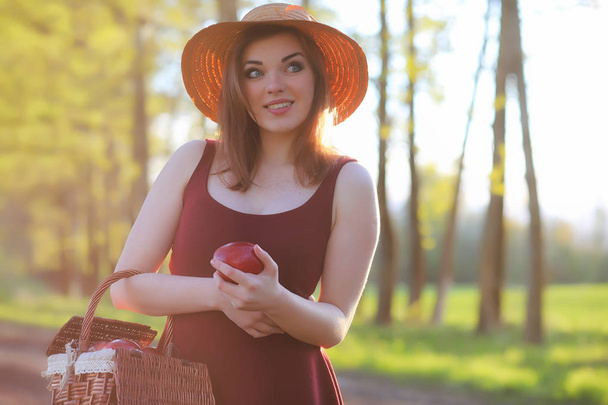 Een meisje in een hoed op een wandeling in het park. Een meisje met een mand-wandeling - Foto, afbeelding