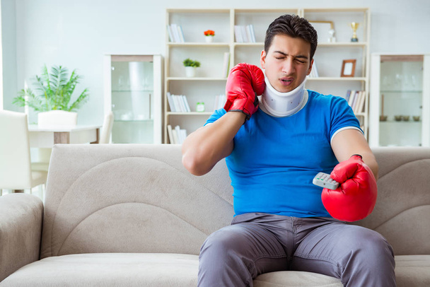 Mies, jolla on niskavamma katsomassa nyrkkeilyä kotona - Valokuva, kuva