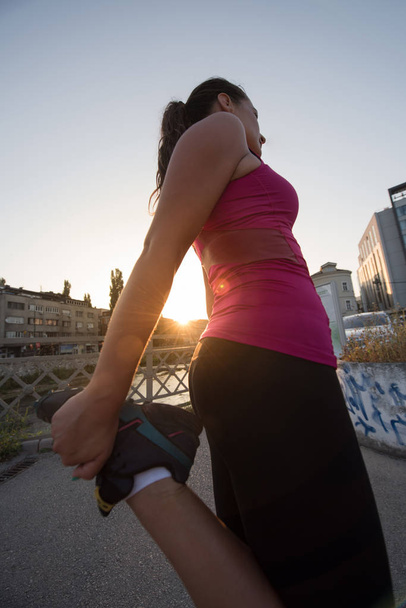 athlete woman warming up and stretching while preparing for running on the city street at  sunny morning - Φωτογραφία, εικόνα