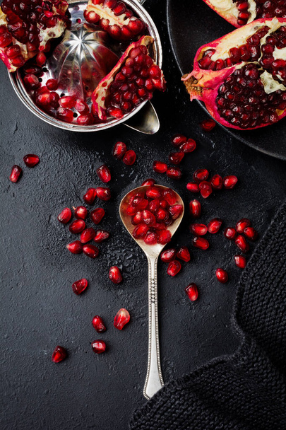 Fresh ripe pomegranate, cut into pieces on black concrete or stone background. Selective focus. Place for text. Top view. - Foto, Imagen