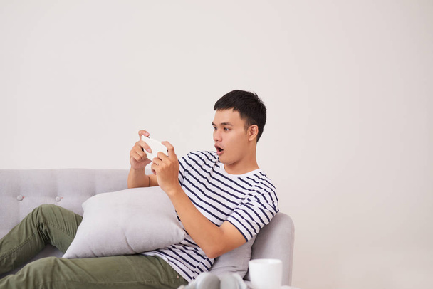 Man with smartphone being surprised as playing games - Photo, Image