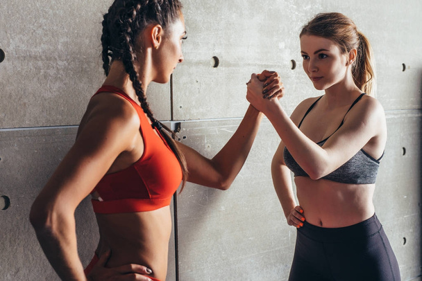 Fit women holding hands with a female opponent looking in her eyes. - Photo, Image