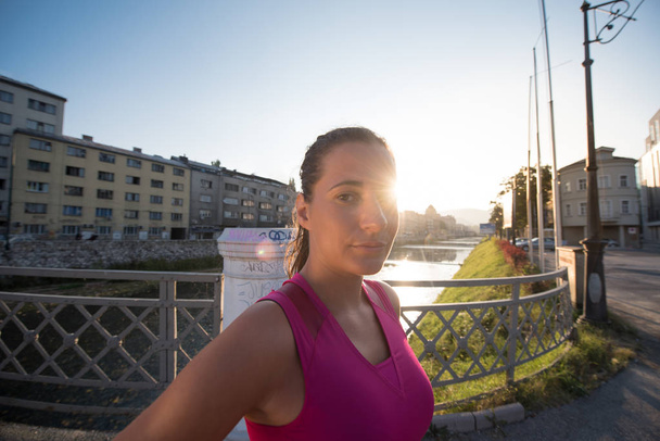 portrait of a young sporty jogging woman at sunny morning in the city - Foto, Imagem