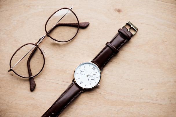 Draufsicht auf Brille und Uhr auf Holzoberfläche - Foto, Bild