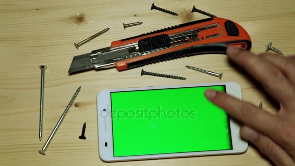 Μια κατασκευή μαχαίρι και smartphone με μια πράσινη οθόνη για το περιεχόμενό σας. - Πλάνα, βίντεο