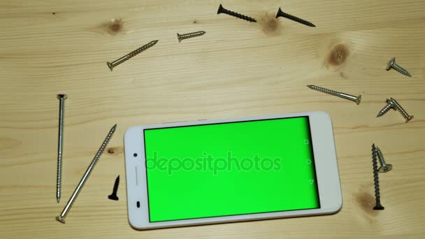 Egy smartphone-val egy zöld képernyőt, egy építési kést, a vágó és csavarok. - Felvétel, videó