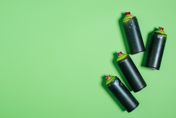 vista dall'alto di lattine disposte con vernice aerosol isolata su verde
 - Foto, immagini