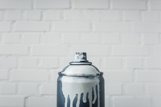 close up vista de tinta aerossol em lata com fundo de parede de tijolo branco
 - Foto, Imagem