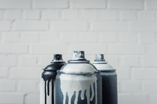 close up view of spray paint in cans with brick wall background - Фото, изображение