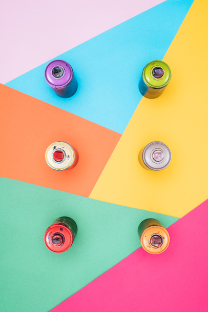 top view of arranged aerosol paint in cans on colorful background - Фото, изображение