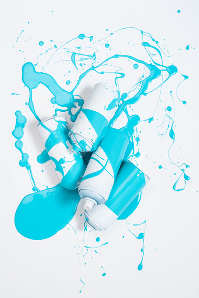 близкий вид распылительной краски в банках, покрытых синей краской, изолированной на белом
 - Фото, изображение
