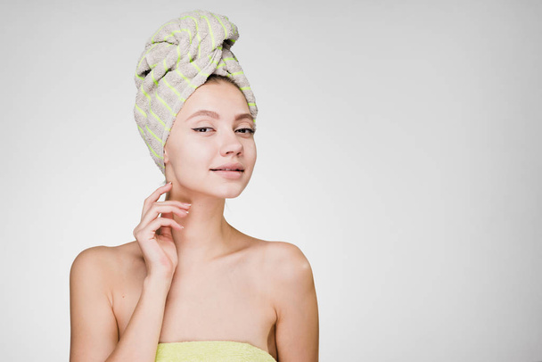 woman with a towel on her head on a gray background - Foto, Bild