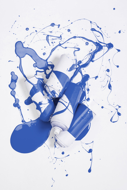 vista de cerca de pintura en aerosol en latas cubiertas con pintura azul aislada en blanco
 - Foto, Imagen
