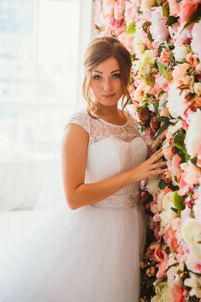 όμορφη νύφη στο φόντο ενός τοίχου με λουλούδια - Φωτογραφία, εικόνα