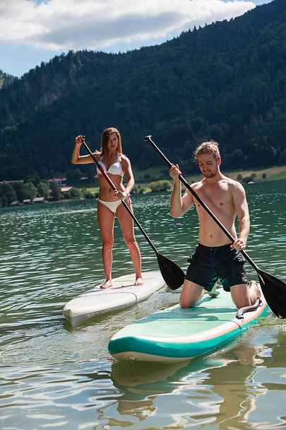 Mann und Frau beim Wassersport mit dem Stand Up Paddle - Foto, Bild