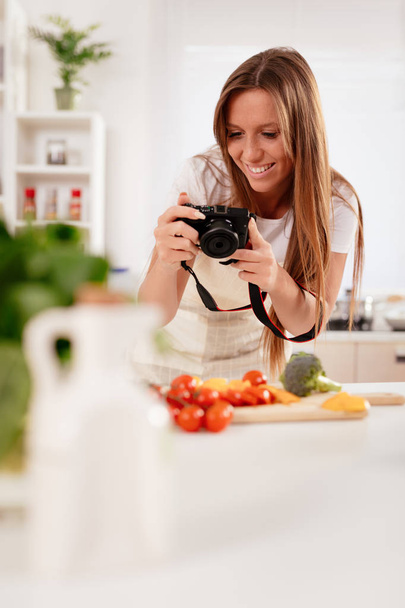 Gyönyörű fiatal nő bevétel fénykép-ból digitális fényképezőgép a blogjában egészséges saláta. - Fotó, kép