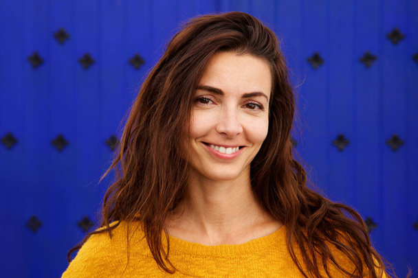 Close up portrait of beautiful young woman smiling against blue background - Foto, Imagem