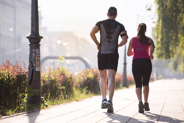 urban sports, healthy young couple jogging  in the city at sunny morning - Фото, изображение