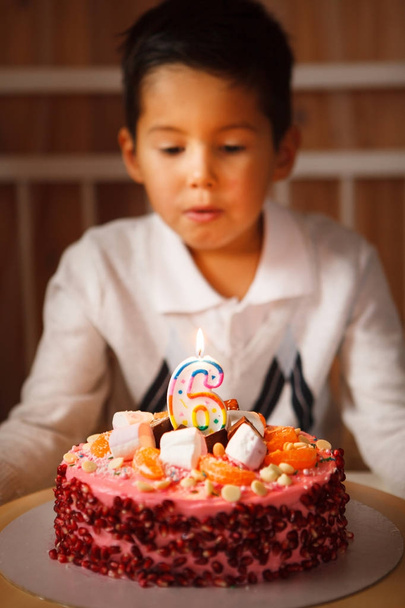 the boy blows out the candles on the cake. - Foto, imagen