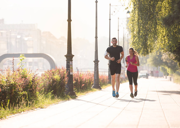 urban sports, healthy young couple jogging  in the city at sunny morning - 写真・画像