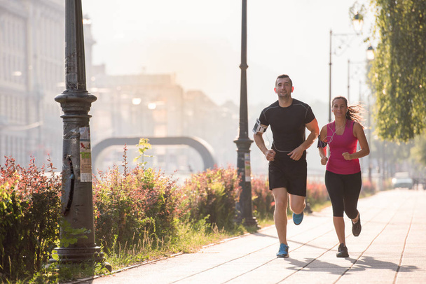 deportes urbanos, saludable pareja joven trotando en la ciudad en la mañana soleada
 - Foto, imagen