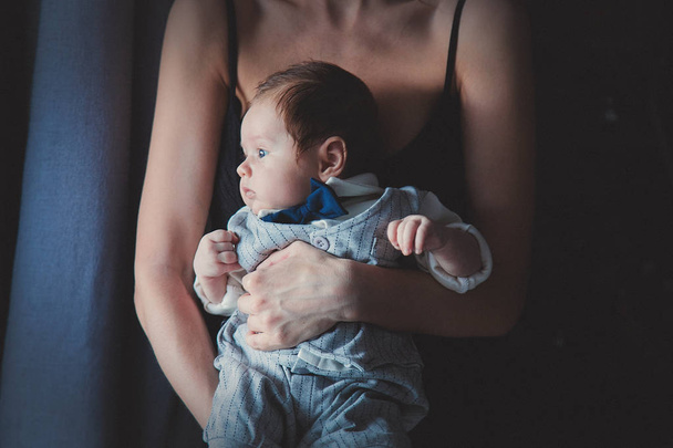 Foto del piccolo neonato nelle mani della madre vicino a una finestra. Immagine realizzata con luce naturale
. - Foto, immagini