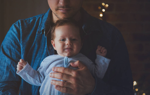 Photo of little infant in father's hands near a window. Image made with natural day light. - Foto, afbeelding