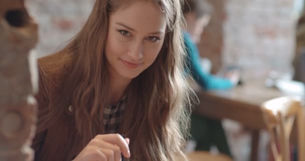 Close up portrait of a young beautiful woman drinking orange juice in cozy restaurant. - Materiał filmowy, wideo
