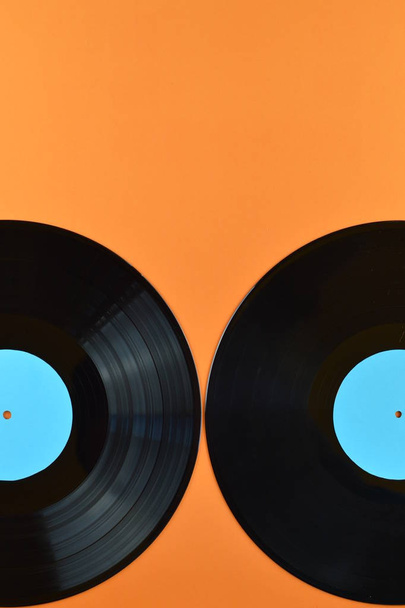 két régi fekete vinil-rekordok az üres cián címkék fele narancssárga háttér - Fotó, kép