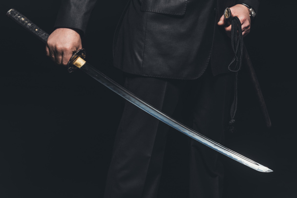περικοπεί shot του ανθρώπου με σπαθί katana σε μαύρο φόντο - Φωτογραφία, εικόνα