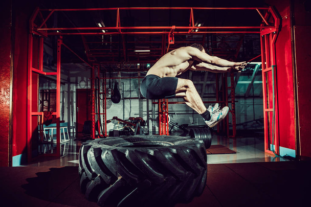 workout man jump in air on tire - Foto, Imagem