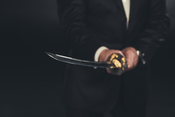 cropped shot of man in suit with katana sword on dark background - Photo, Image