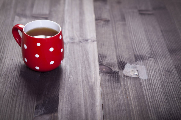 the Red cup in a white point is on a white wooden table. Paper hearts hang on the wall - Foto, imagen