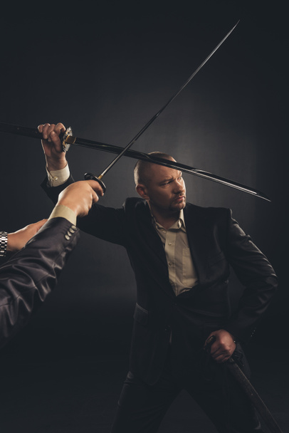 strong mature businessman fighting with katana sword isolated on black - Photo, Image