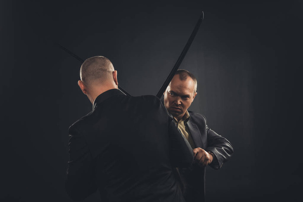 hommes d'affaires se battant avec des épées katana isolés sur noir
 - Photo, image