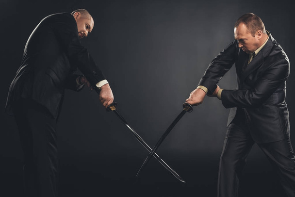 Geschäftsleute kämpfen mit Katana-Schwertern auf Schwarz - Foto, Bild