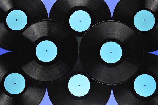 Stapel alter schwarzer Schallplatten mit leeren Cyan-Etiketten auf blauem Hintergrund - Foto, Bild