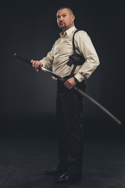 Seitenansicht eines Yakuza-Mitglieds, das sein Katana-Schwert zückt - Foto, Bild