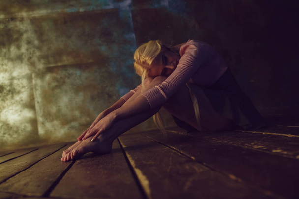 Beautiful blonde woman is sitting on the wooden floor. - Φωτογραφία, εικόνα