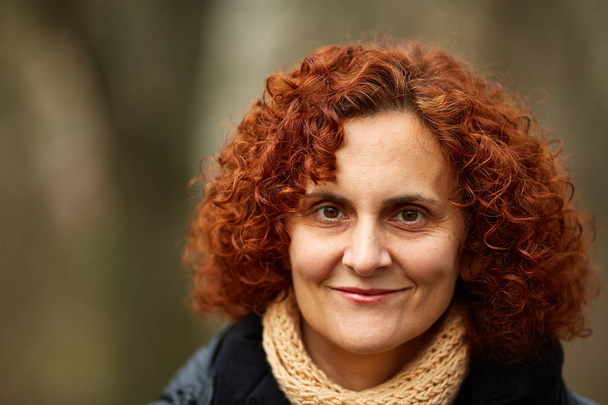 Closeup of a curly red haired middle aged woman outdoor - Foto, Imagen