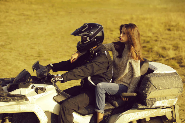 Handsome man and pretty girl ride quad bike on field road on natural background - Foto, imagen