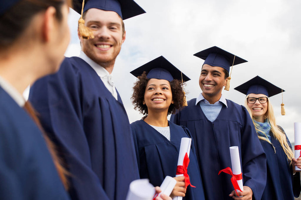 Glückliche Studenten in Mörteltafeln mit Diplomen - Foto, Bild